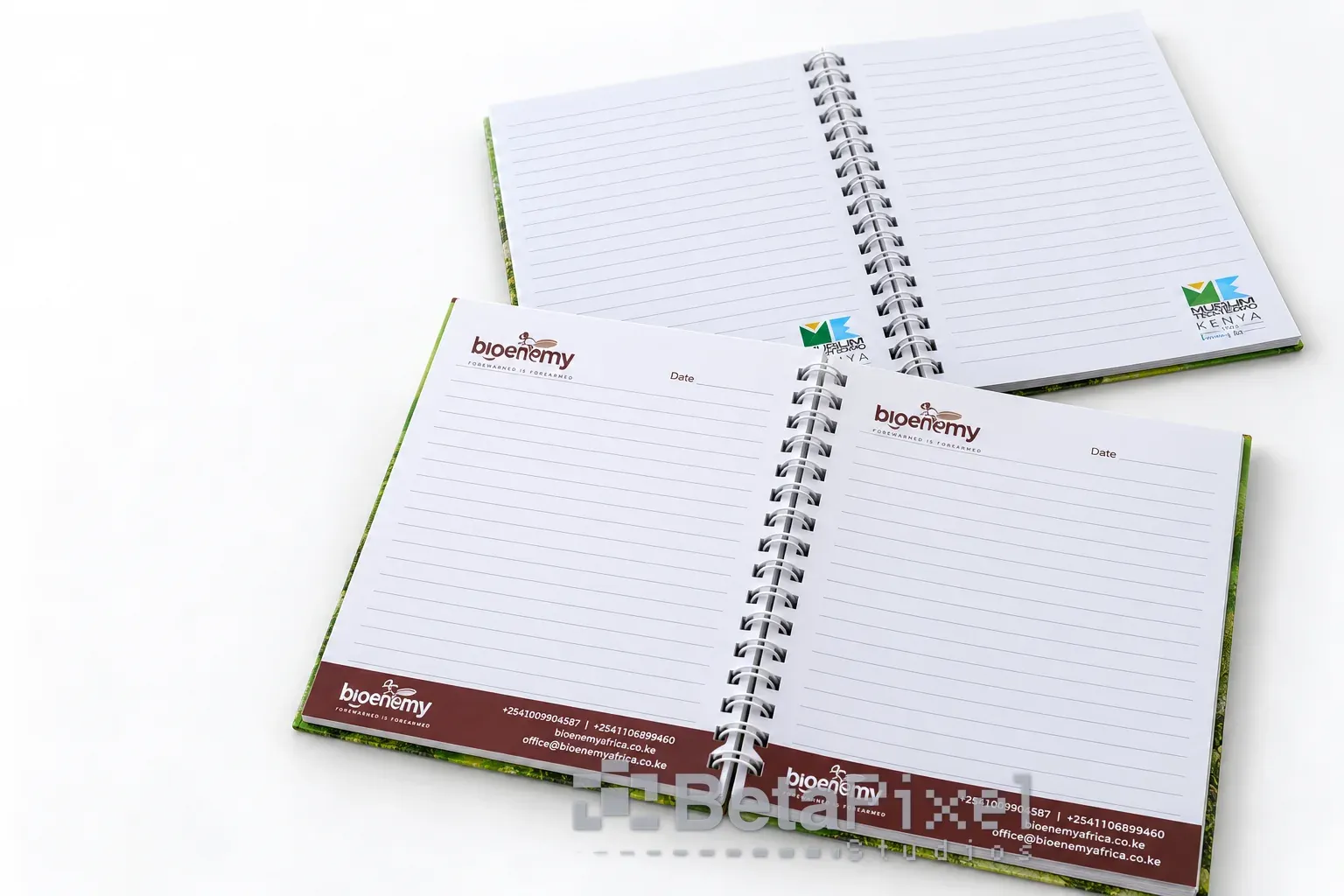 Open spiral notebooks showing ruled inner pages with a company logo header and a printed contact footer