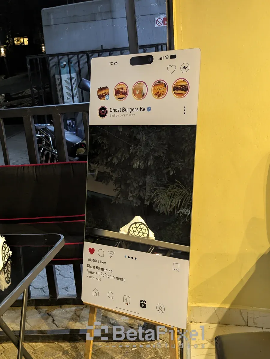 Social media frame selfie mirror on a wooden easel outside a restaurant at night