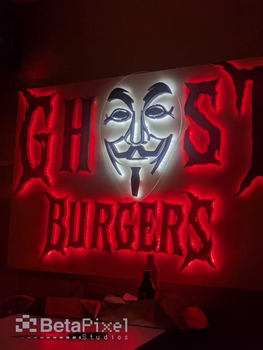 Restaurant wall sign with red 3D lettering and a white mask logo, lit from behind with a red glow